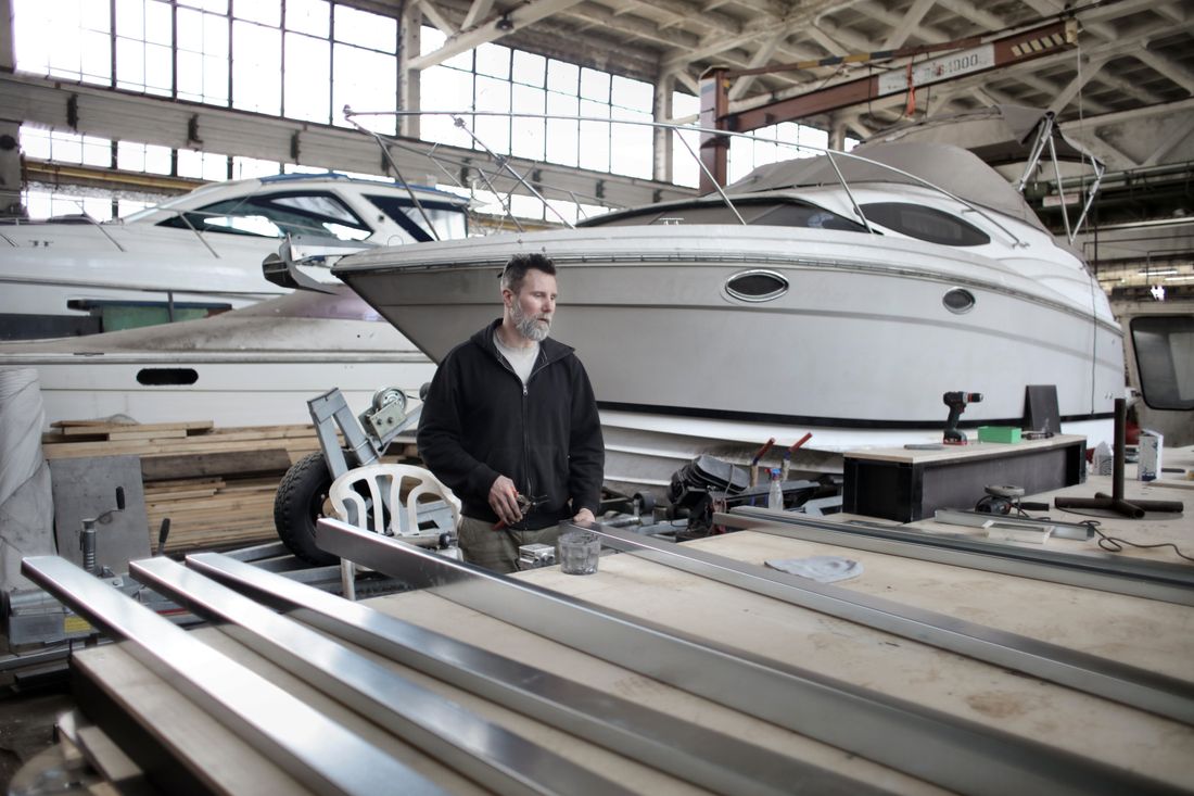 Marine mechanic working on hardware beside a boat