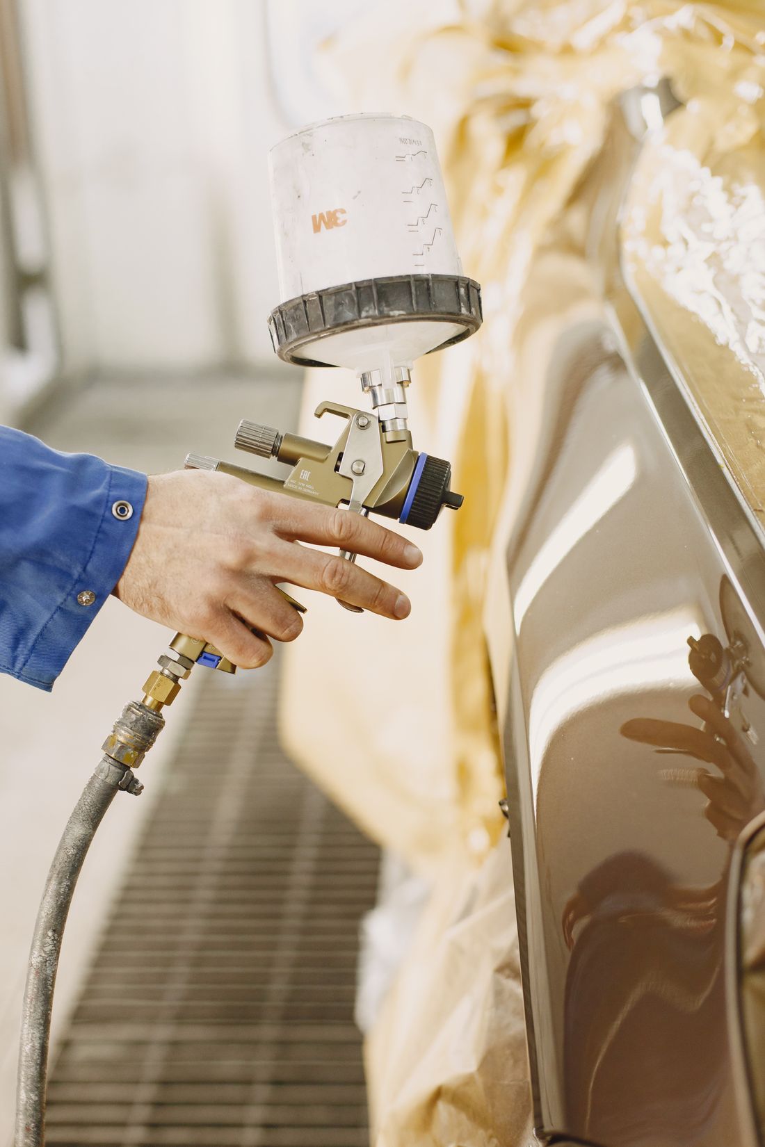 Technician spray-painting a vehicle in a paint booth